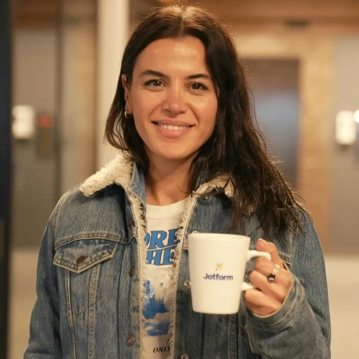 A lady with a cup of coffee in her hand, ready to start working